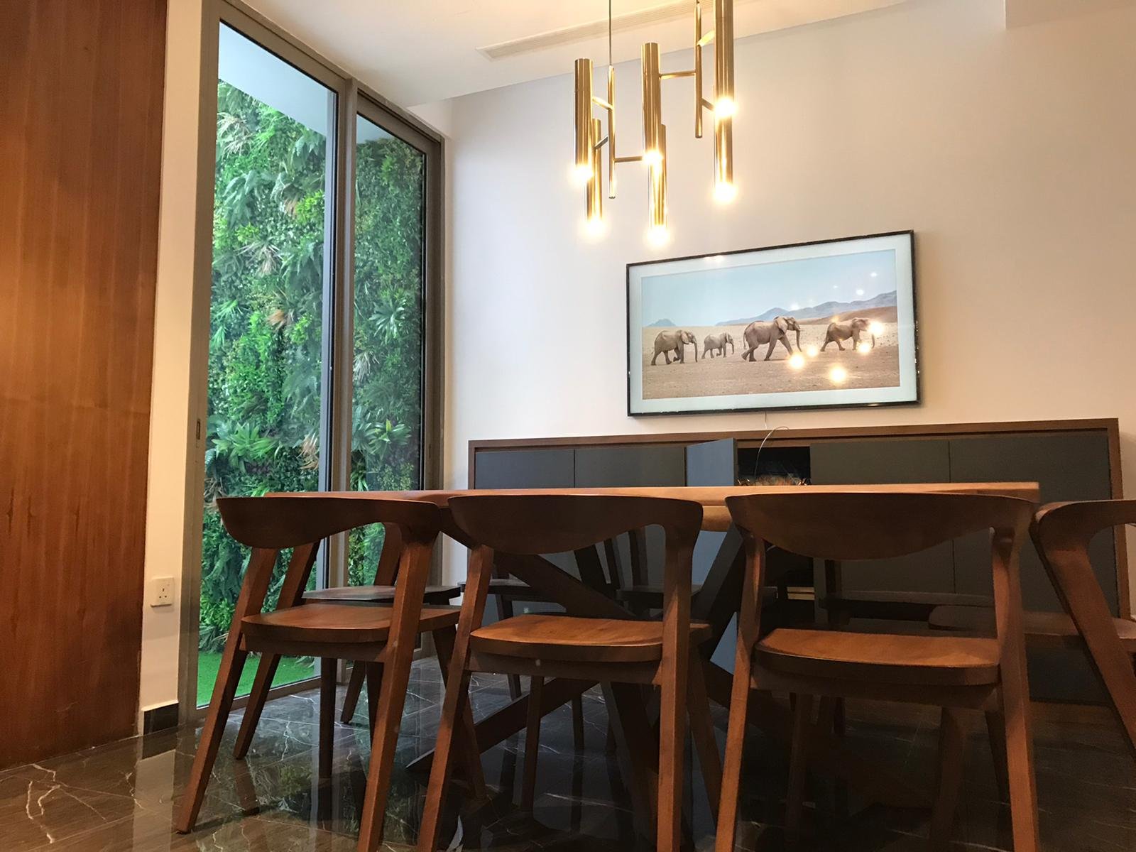 Dining room at The Woods with timber furniture, pendant lighting and full-height garden glazing